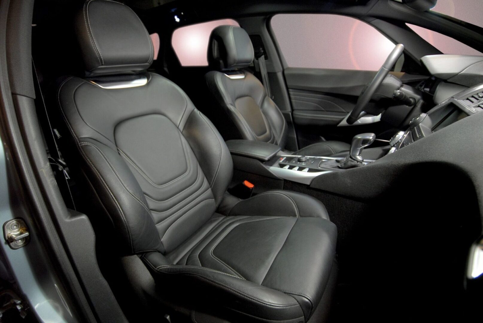 A car with black leather seats and the door open.
