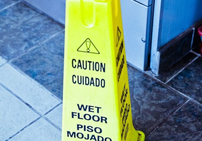 A yellow caution sign on the floor of a building.